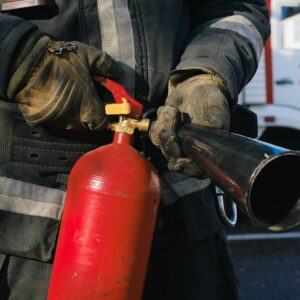 Firefighter in uniform holding a fire extinguisher, emphasizing safety and emergency readiness.